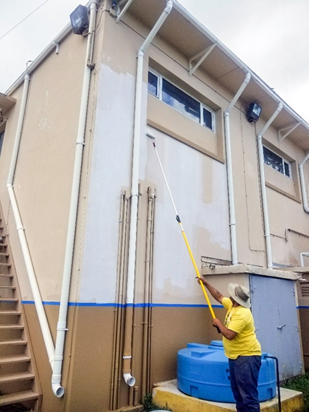 Worker painting a building for Hurricane Maria Repairs